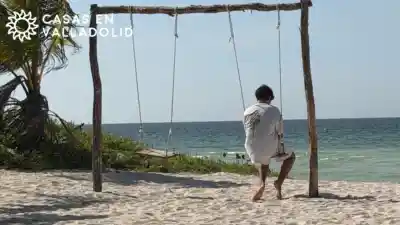 Adolescente sentado en un columpio frente al mar durante una salida familiar desde Valladolid, Yucatán